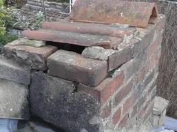 Storm-damaged chimney stack with loose brickwork before repair